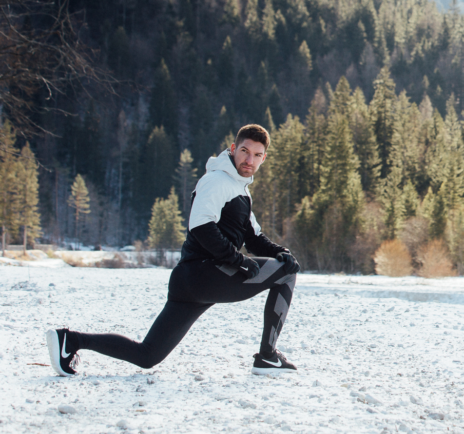 A Reset Studio athlete stretching outdoors on a snow-covered mountain meadow