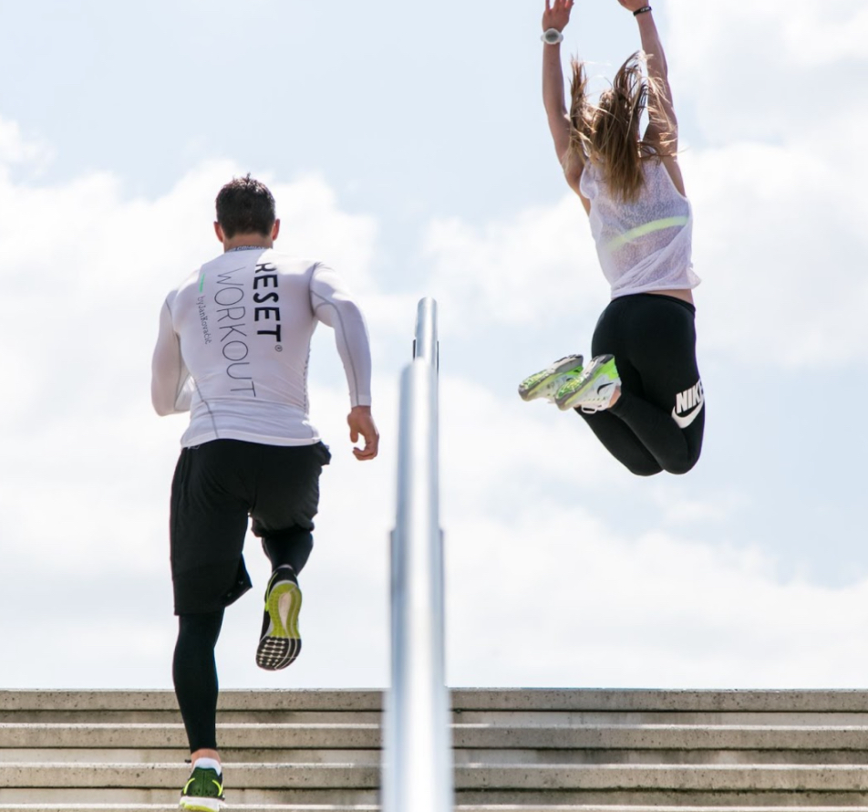 Two Reset members running and jumping outdoors on a bright day